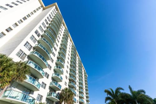a tall white building with palm trees in the foreground at Sunny Isles Ocean Reserve Condo Apartments in Miami Beach