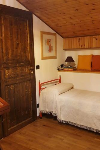 a bedroom with two beds and a wooden door at ViviMontagna Mathilda in Perosa Argentina