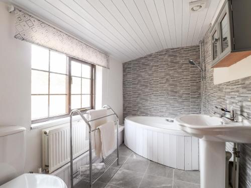 a white bathroom with a tub and a sink at Barn Court Cottage in Narberth