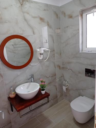 a bathroom with a sink and a toilet and a mirror at Vasiliu Boutique Hotel Ksamil in Ksamil