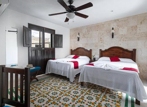een slaapkamer met 2 bedden en een plafondventilator bij La Aurora Hotel Colonial in Valladolid