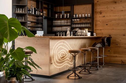 a bar with stools in front of a counter at Hotel FoKus in Sankt Jakob in Defereggen