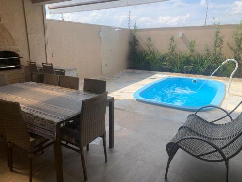 een patio met een tafel en stoelen en een zwembad bij Tati's house Olímpia-casa para até 11 pessoas in Olímpia