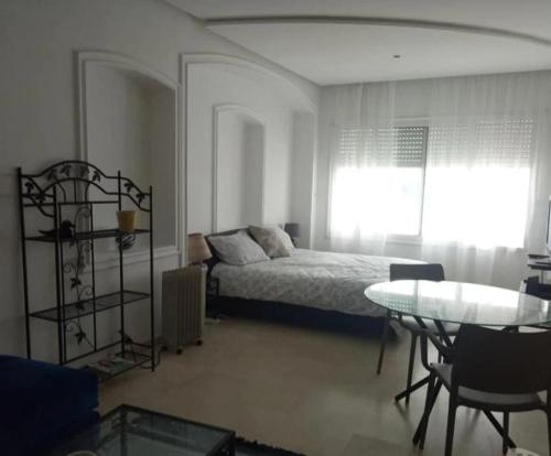 een slaapkamer met een bed, een tafel en een raam bij Taouima bienvenue in Nador