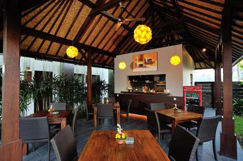 um restaurante com mesas e cadeiras de madeira e um bar em Ganga Hotel & Apartment em Denpasar