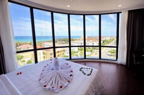 um quarto com uma cama branca e uma grande janela em Sunflower Hotel Phú Yên em Tuy Hoa