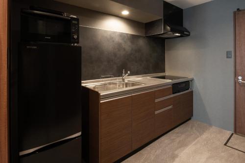 cocina con fregadero y nevera negra en Good Neighbors, en Kanazawa