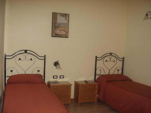 two beds in a bedroom with red sheets and a picture at B&B Valoroso Village in Licata