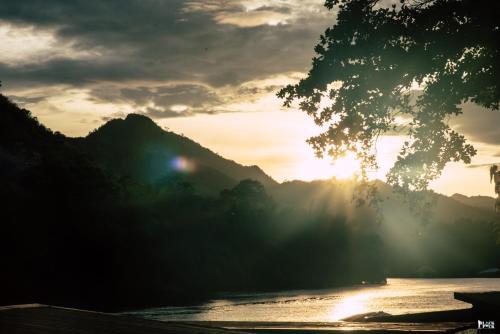 a sunset over a river with mountains in the background at ชอว์ งาทอง รีสอร์ต Chor Ngar Thong Erawan Kanchanaburi in Kanchanaburi
