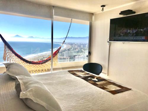 a bedroom with a hammock in front of a large window at La Choza VIP Roja in Coquimbo