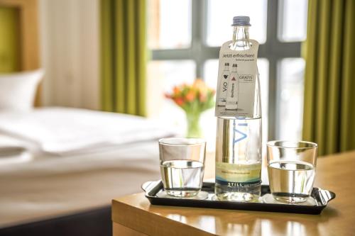 a bottle and glasses on a tray on a table at H+ Hotel 4Youth in Berlin