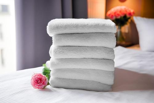 a stack of towels sitting on top of a bed at H+ Hotel 4Youth in Berlin