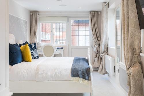 ein Schlafzimmer mit einem weißen Bett mit blauen und gelben Kissen in der Unterkunft Elimonn Bloom in Kent