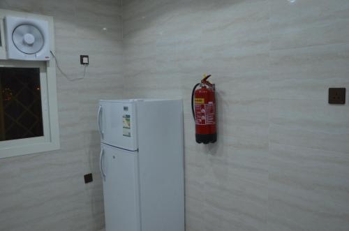 a fire extinguisher hanging on a wall next to a refrigerator at الوان للشقق المخدومة in Khamis Mushayt