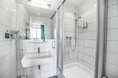 a white bathroom with a sink and a shower at H+ Hotel 4Youth in Berlin