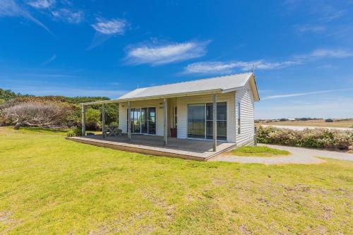 a small house with a porch on a grass field at Cottages for Couples in Port Fairy