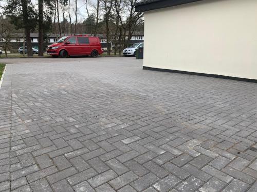 a brick parking lot with a red van parked next to a building at 5 Bed Camberley Airport Accommodation in Camberley