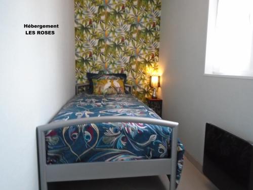 a small bedroom with a bed with a floral wallpaper at La Petalerie in Épernay