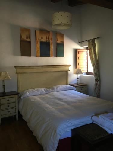 um quarto com uma grande cama branca e duas mesas de cabeceira em Casa Clemente I em La Hiruela