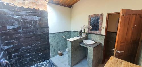 La salle de bains est pourvue d'un lavabo et d'un mur en pierre. dans l'établissement Villa Esa Ubud, à Ubud