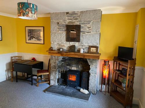 a living room with a stone fireplace and a desk at Holly Cottage in Glencoe