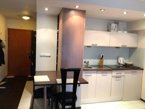 a kitchen with white cabinets and a table with chairs at Apartament 117 in Krynica Zdrój