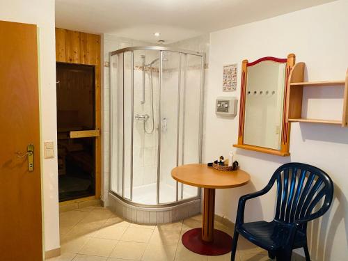 a bathroom with a shower with a table and a chair at Haus Wagrain in Wagrain