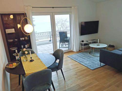 a living room with a table and chairs and a television at MAISON AMAND - Am See mit Privatstrand in Immenstaad am Bodensee