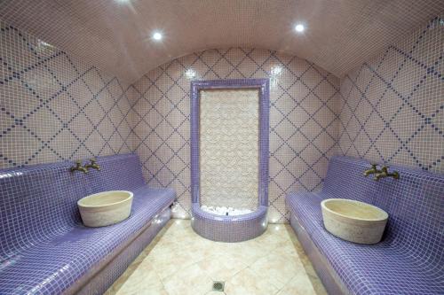 a bathroom with purple benches and a tub and a sink at Izida Palace Apartments in Sunny Beach