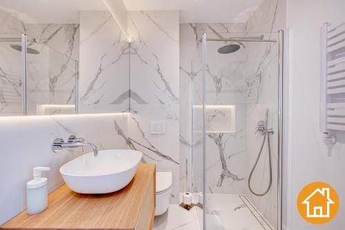 a white bathroom with a sink and a shower at Apartamenty Marea - visitopl in Międzyzdroje