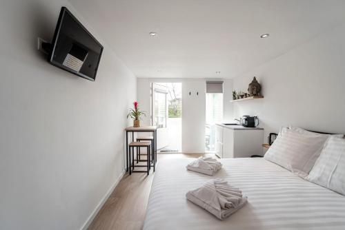 ein weißes Schlafzimmer mit einem Bett mit zwei Handtüchern darauf in der Unterkunft Little Buddha in Zandvoort