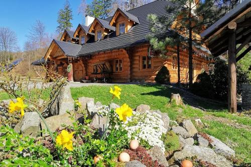 una cabaña de madera con flores delante en Jaszowianka Best For You en Ustroń