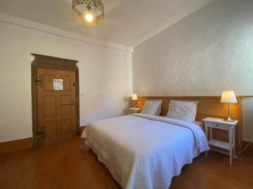 a bedroom with a white bed and a table and lamp at Le p'tit relai in Montbozon