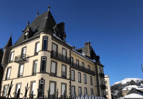 a large white building with a black roof at Le Grand Hôtel Mont Dore in Le Mont-Dore