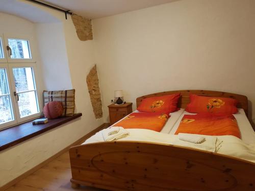 a bedroom with a wooden bed with orange pillows at Gästehaus Vergissmeinnicht in Guteborn