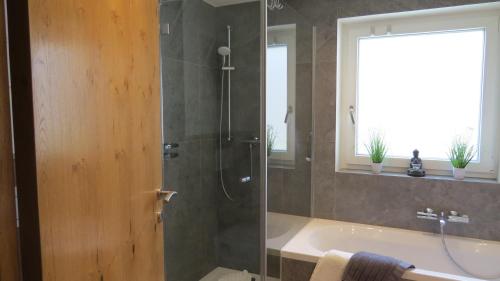 ein Badezimmer mit einer Dusche, einer Badewanne und einem Waschbecken in der Unterkunft Chalet Hackl in Sautens