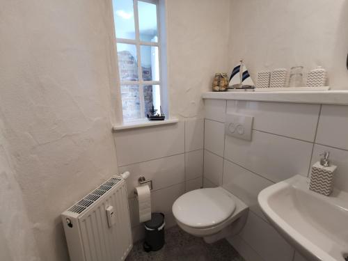 a white bathroom with a toilet and a sink at Gästehaus Vergissmeinnicht in Guteborn