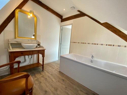 uma casa de banho com uma banheira, um lavatório e um espelho. em Manoir de L'Oiselière em La Remuée