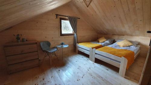 a bedroom with two beds and a table in a attic at ZACISZE ,,Jastrząb'' domek na Kaszubach z balią z jacuzzi in Brodnica Dolna