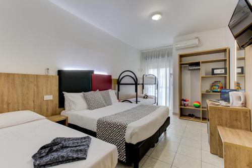 a hotel room with two beds and a television at Hotel Grazia Riccione in Riccione