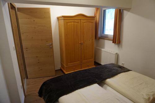 a bedroom with a bed and a wooden cabinet at Appartementhaus Hüttenberger in Erpfendorf
