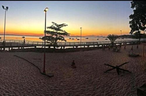a beach at sunset with a pier and a tree at ReCanto dos Passáros - Guaratiba in Pedra de Guaratiba