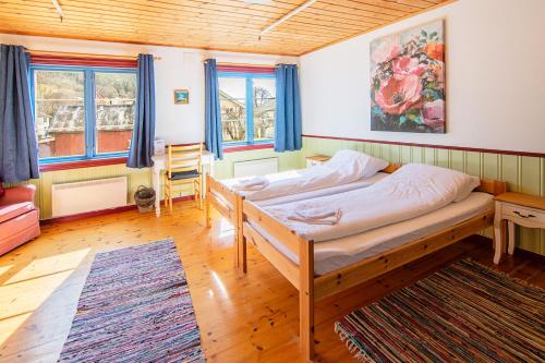 Un dormitorio con una cama, un escritorio y ventanas. en Fyresdal Gjestehus, en Moland