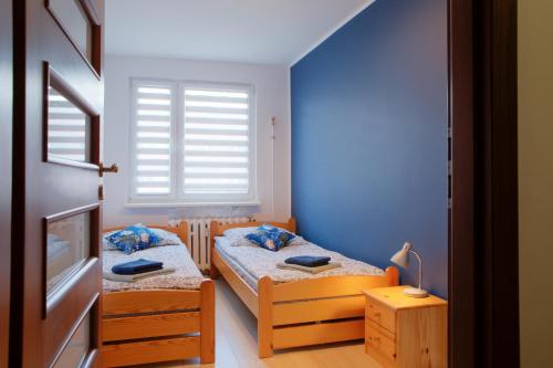 1 dormitorio con 2 camas y pared azul en May Land Apartment en Szklarska Poręba