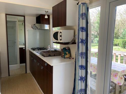 une cuisine avec un évier et une cuisinière four supérieur dans l'établissement Mobil-Home Saint Cheron, à Saint-Chéron