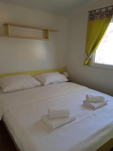 1 cama blanca grande con 2 toallas blancas. en Naturist Mobile Homes Eden in FKK Ulika, en Poreč