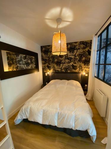 a bedroom with a large white bed and a lamp at Le clos de l'Embellie in Lorient