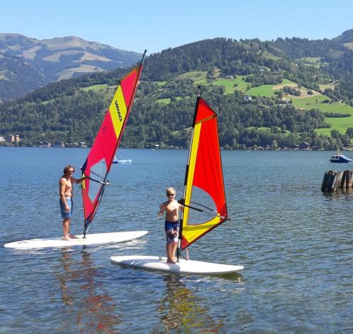 two people on surfboards with sails in the water at Aparthotel Pinzgau in Neukirchen am Großvenediger