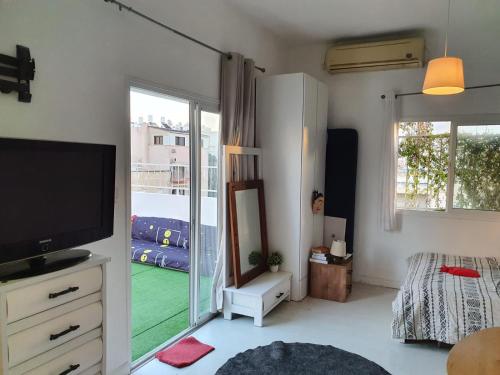 a living room with a television and a balcony at Hostel BU93 in Tel Aviv
