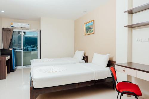 a bedroom with two beds and a red chair at Corner One Residence in Hat Yai